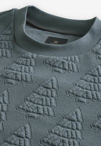 Gray sweatshirt featuring a textured pattern of raised triangles, with a crew neckline and ribbed cuffs and hem. Soft, knit fabric.