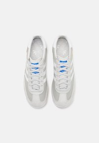 Szare sneakersy z białymi akcentami, wykonane z zamszu i materiału syntetycznego, o okrągłym nosku, czterema oczkami i wzorzystą wkładką z logo Adidas.
