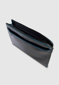 Clutch de cuero negro con acentos turquesa, con cierre de cremallera y un compartimento abierto, textura suave y diseño minimalista.