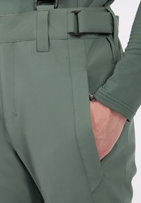 Groene technische broek met een strak ontwerp, gladde textuur en een verstelbare taille met een gesp. Inclusief zijzakdetails.