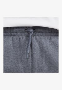 Szare dresy z elastycznym pasem, z sznurkiem zakończonym szarymi agletami. Materiał ma miękką, teksturowaną powierzchnię.