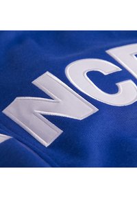 Blauwe sporttrui met witte geborduurde letters. De stof heeft een gladde textuur en gelijkmatige stiksels. Het ontwerp benadrukt de letters prominent.