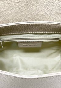 Borsa a tracolla in pelle beige con texture, foderata internamente in modo liscio e dotata di una tasca con zip. L'interno è di colore chiaro, offrendo ampio spazio di archiviazione.
