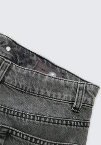 Szare dżinsy z denimu o teksturowanej powierzchni, pięciopunktowym kroju, kontrastowym przeszyciu i metalowym zapięciem na guzik.