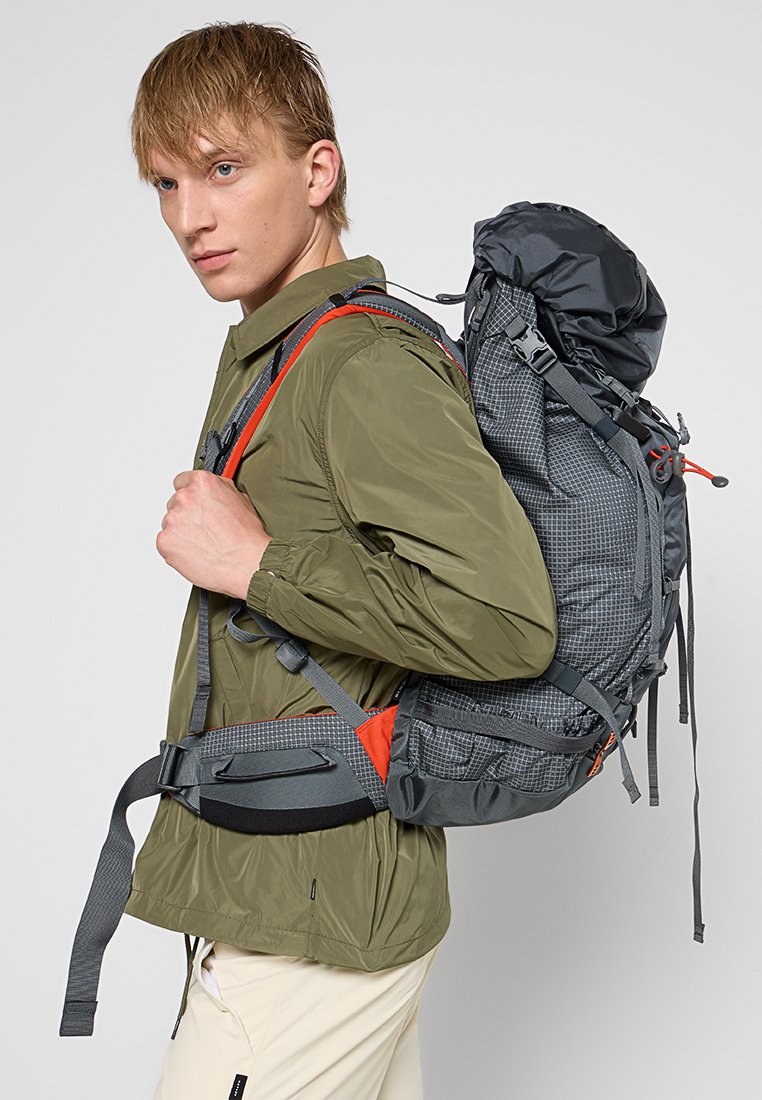 Rugzak met een grijs patroon, verstelbare schouderbanden en rode accenten. Beschikt over een oprolbare sluiting en een gevoerde heupband voor comfort.