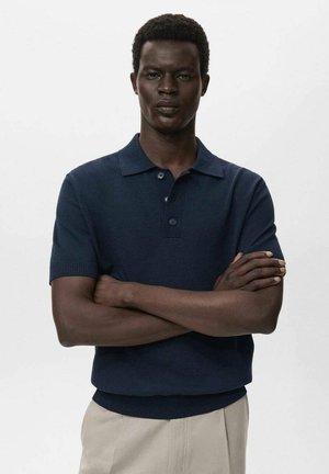 Polo shirt blu navy a maniche corte con colletto piatto, patta con tre bottoni, polsini a coste e una trama di maglia liscia.