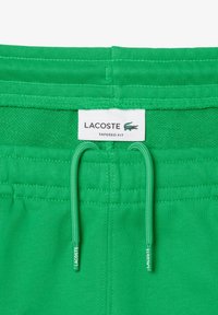 Zöld, tapered fit rövidnadrág, elasztikus derékrésszel, kötőfűzős kialakítással, Lacoste logóval. Simas textúra és díszítetlen dizájn.