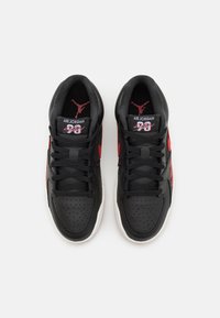 Sneaker in pelle nera con accenti rossi, punta perforata, lacci neri piatti e suola in gomma bianca. Presenta il logo sulla linguetta e sul lato.