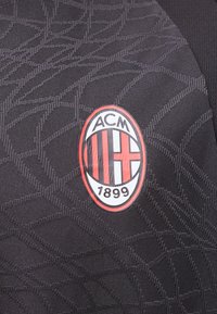 Λογότυπο ποδοσφαιρικής ομάδας AC Milan με κόκκινες και μαύρες ρίγες και το έτος 1899 σε μαύρο φόντο με υφαντό μοτίβο.