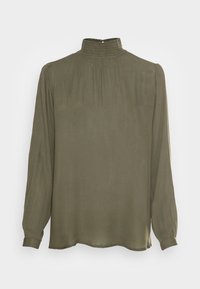 Blouse vert olive avec un col montant smocké, manches longues et tissu fluide. Texture lisse et coupe décontractée.