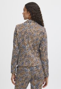 MusterBlazer mit einer Mischung aus braunen, schwarzen und hellblauen Punkten. Taillierte Passform mit einer glatten Textur und geschlitztem Revers.