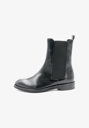 Zwarte leren enkelboot met elastische zijkanten, ronde neus en een lage, platte rubberen zool. Voorzien van een lussen aan de achterkant voor gemakkelijk aan- en uittrekken.