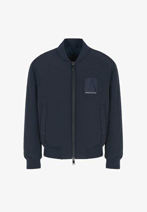 Giacca bomber navy con zip frontale, polsini a coste e logo a patch sul petto. Realizzata in un tessuto morbido con una texture liscia.