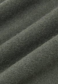 Pelēks teksturēts audums ar mīkstu, austu apdari. Materiālam ir ribota raksta un smalka spīduma efekts, radot dziļumu krāsā.