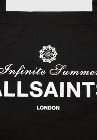 Borsa tote nera in tela con grande testo bianco che recita "ALLSAINTS" e "Infinite Summer", accompagnato da dettagli decorativi del logo sopra.