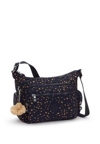 Bolso navy con patrones de estrellas doradas, material de tela, correa ajustable, múltiples bolsillos con cremallera y un llavero de mono de peluche adjunto.
