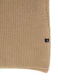 Knit dešinė spalva su vertikalios įdėtos tekstūros, turinti ištrupėjusią kraštą ir mažą juodą etikėtę su balta žvaigžde apatinėje kampe.