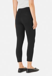 Zwarte leggings van rekbaar materiaal, met een aansluitend ontwerp, hoge tailleband en een lengte tot de enkels. Flexibele en soepele textuur.