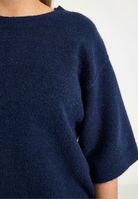 Granatowy sweter dzianinowy z okrągłym dekoltem, krótkimi rękawami i miękkim, teksturowanym wykończeniem. Idealny na casualowe okazje.