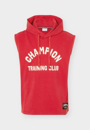 Punainen hihaton hupullinen collegetakki, jossa on valkoinen "CHAMPION TRAINING CLUB" -teksti ja edessä kiristysnyörit, sekä musta pieni etiketti helmassa.