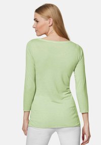 Helles grünes Langarmshirt mit lockerer Passform, rundem Halsausschnitt und weicher Textur; verfügt über einen leicht abgerundeten Saum und minimalistische Nähte.