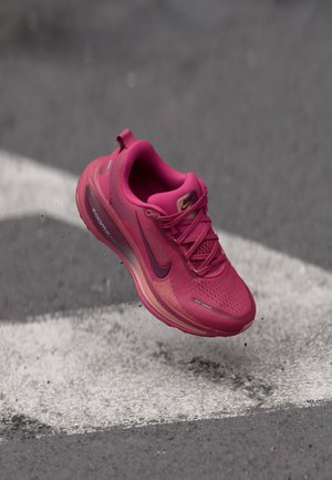 Pink running shoe with a textured mesh upper, cushioned midsole, and rubber outsole. Features a logo on the side and lacing system.
