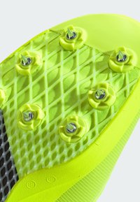 Suola di scarpa da corsa gialla brillante con motivo a griglia, con punte metalliche e accenti testurizzati, progettata per trazione e stabilità.