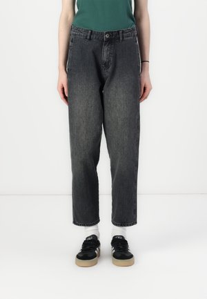 Sorte denim jeans med løs passform, med knappelukking, beltehemper og sidelommer, kombinert med sorte joggesko.