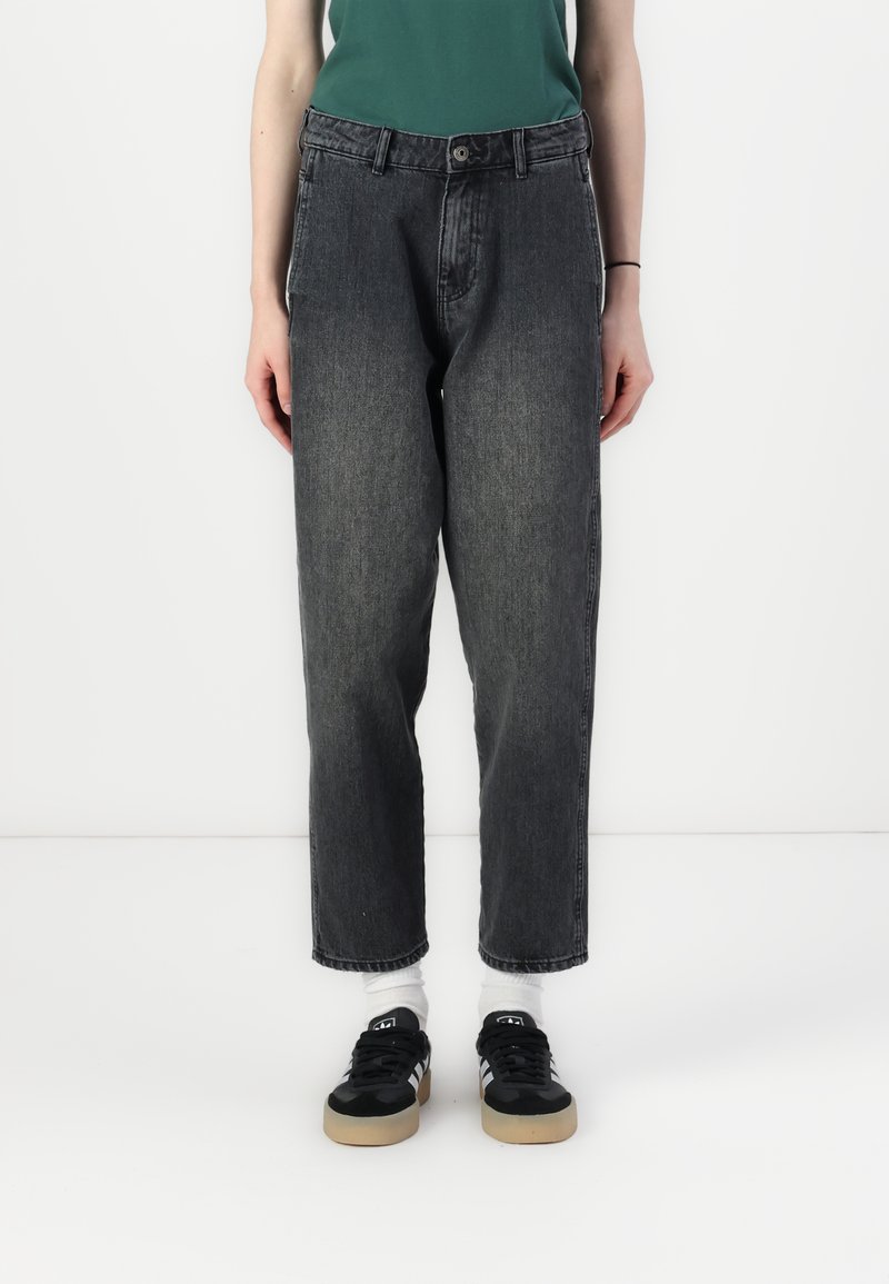 Černé džíny z denimu s volným střihem, se zapínáním na knoflík, poutky na opasek a bočními kapsami, doplněné černými teniskami.