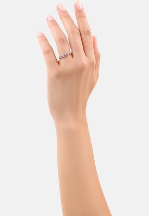 Anillo de plata con una banda delgada y una fila de pequeñas piedras claras, llevado en una mano con un tono de piel claro, sobre un fondo blanco liso.