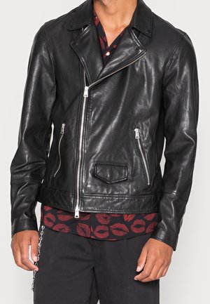 Veste de moto en cuir noir avec un col cranté, une fermeture éclair à l'avant et deux poches latérales ; présente un matériel minimal et une texture lisse.