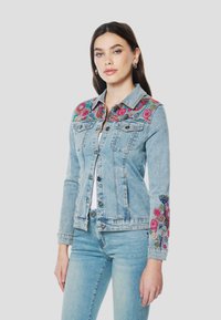 Hellblaue Jeansjacke mit mehrfarbiger Blumenstickerei auf Schultern und Ärmeln, ausgestattet mit zwei Fronttaschen und Knopfverschluss.