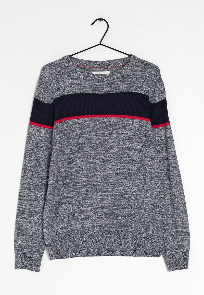 Pull en maille gris à manches longues avec une bande horizontale bleu marine et de fines lignes rouges sur la poitrine et le haut des bras, suspendu à un cintre noir.