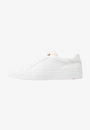 Baskets basses en cuir blanc avec lacets blancs, semelle en caoutchouc épaisse et détails de couture minimalistes le long du talon et du panneau latéral.