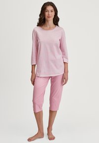 Roze geblokt pyjama-top met driekwartmouwen, gecombineerd met effen roze capri-broek, gemaakt van zachte, lichte stof.