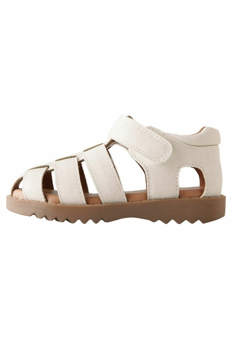 Hvid sandal lavet af struktureret materiale med flere udsparinger, Velcro-rem og en robust tan gummisål. Tilbyder en sikker pasform.