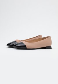Baleriny z matowej, cielistej skóry na górze oraz czubkiem z lakierowanej czarnej skóry. Posiadają niski blokowy obcas.