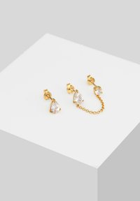 Orecchini in oro con cristalli trasparenti a forma di pera e una catena di collegamento. Texture liscia e finitura lucida.