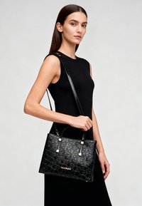 Borsa nera con motivo del logo in rilievo, forma rettangolare elegante, manici superiori e tracolla rimovibile. Dettagli hardware dorati.