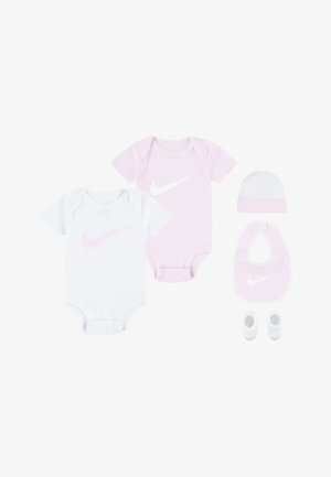Due bodysuit per neonati (uno bianco, uno rosa) con logo Nike, un cappellino bianco, un bavaglino rosa e scarpine bianche. Materiale in cotone, texture morbida.