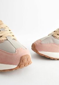 Rosa och grå sneakers med en ovandel i mocka och mesh, texturerade snören och en gummisula med ett mönstrat mönster.