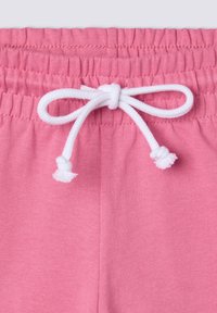 Shorts di cotone rosa con elastico in vita e coulisse bianca, arricchiti da dettagli con pompon. Texture liscia e design semplice.