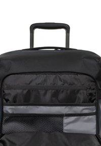 Interieur van een zwarte reistas met meerdere vakken: een vak met rits, een vlak paneel in grijs en een meshgedeelte voor organisatie. Uittrekbare handgreep bovenaan.