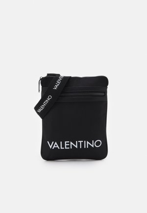 Zwarte rechthoekige crossbodytas met voorvak met rits en brede band bedrukt met "VALENTINO" in witte letters.