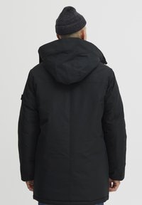 Sort puffjakke med hætte, designet med en glat tekstur, med en mellemlang længde og omfavner ryggen.