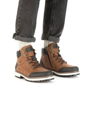 Brown leather hiking boots with black rubber toe caps, metal eyelets, and a side zipper. Features a white and black treaded sole.