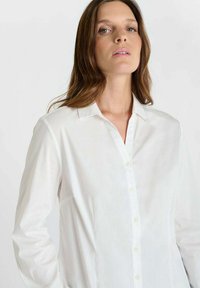 Witte overhemd met zachte textuur, gestructureerde kraag, lange mouwen en een klassieke pasvorm. Voorzien van subtiele stikseldetails.