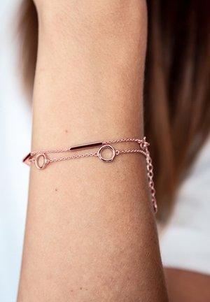 Pulsera de oro rosa con eslabones, que presenta acentos circulares y un diseño de barra pulida. Textura suave, estilo minimalista.