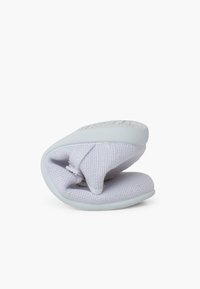 Weiche, weiße Slipper mit einem strukturierten Stoff-Obermaterial und einer flexiblen Gummisohle, die ein rundes Design und gestickte Akzente aufweisen.
