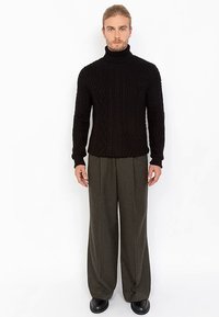 Black cable-knit turtleneck sweater paired with gray wide-leg trousers and black shoes. Focus on texture and contrast between materials.